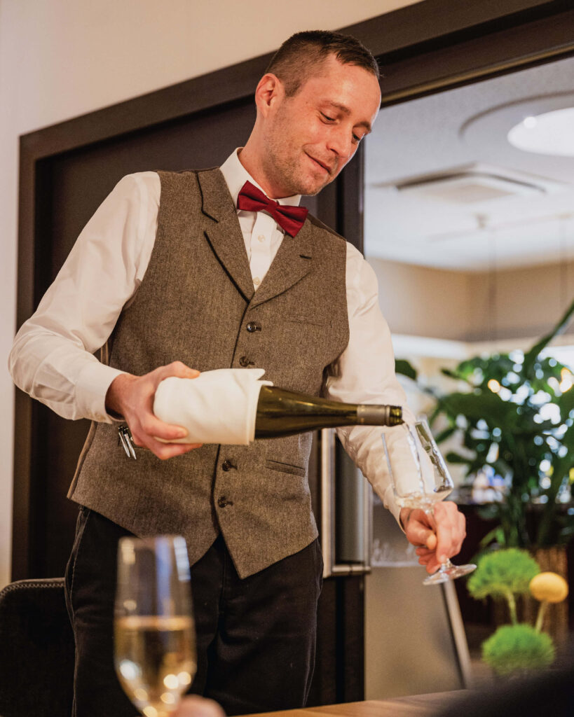 Restaurant-Das-Muehlentor-Kellner-giesst-Weisswein-in-ein-Glas-fuer-einen-Gast