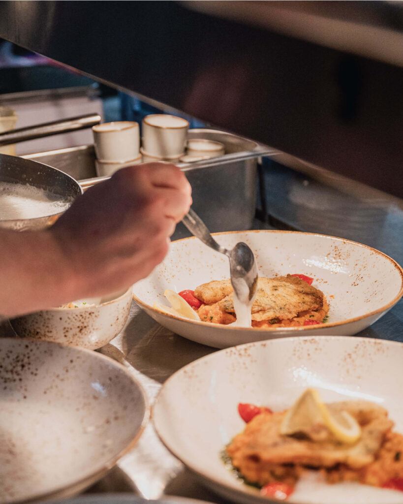 Restaurant-Das-Muehlentor-Koch-richtet-Essen-unter-der-Waermelampe-an (1)
